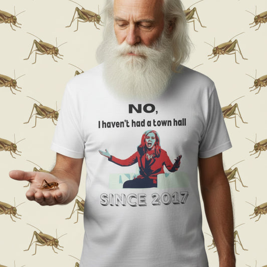 Old man with white hair and white beard wearing a white t-shirt with a Marsha Blackburn graphic design and black text that says 'No, I haven't held a town hall since 2017' on a white background.