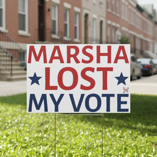 Political protest sign on grass with a row of townhouses in the background